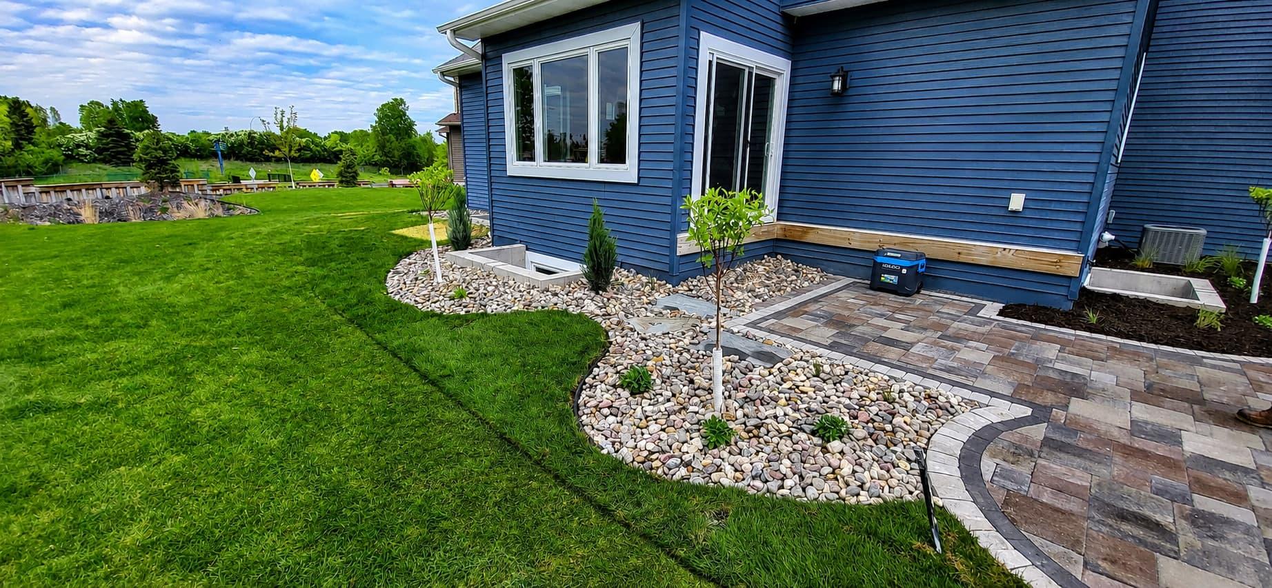 River-rock landscape beds with new sod and a paver walkway